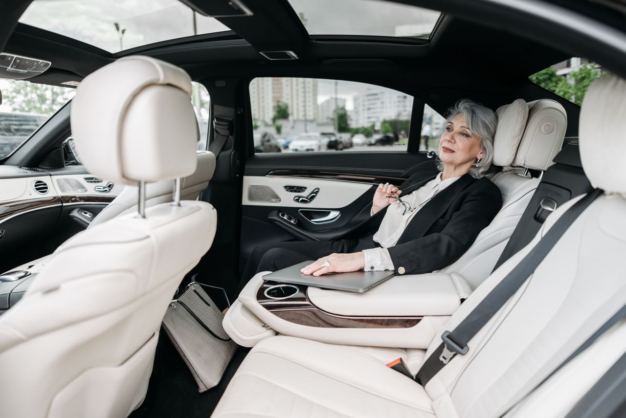 Senior woman relaxing in a luxurious car interior, enjoying the comfort and modern design.